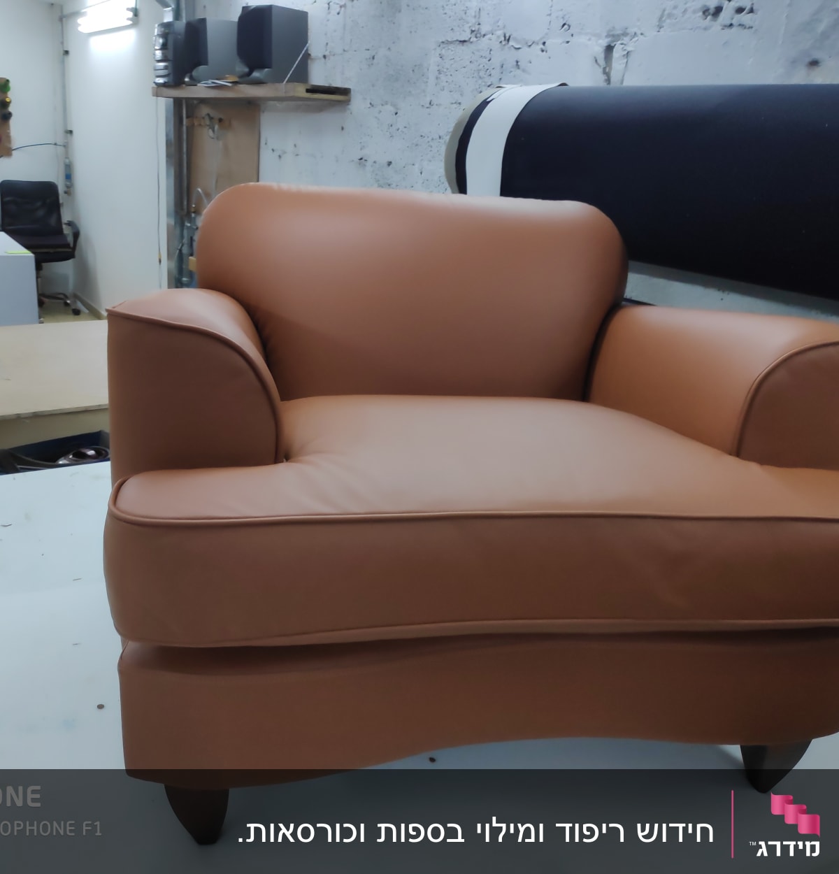 כורסה מרופדת בעור חום בסטודיו לריפוד